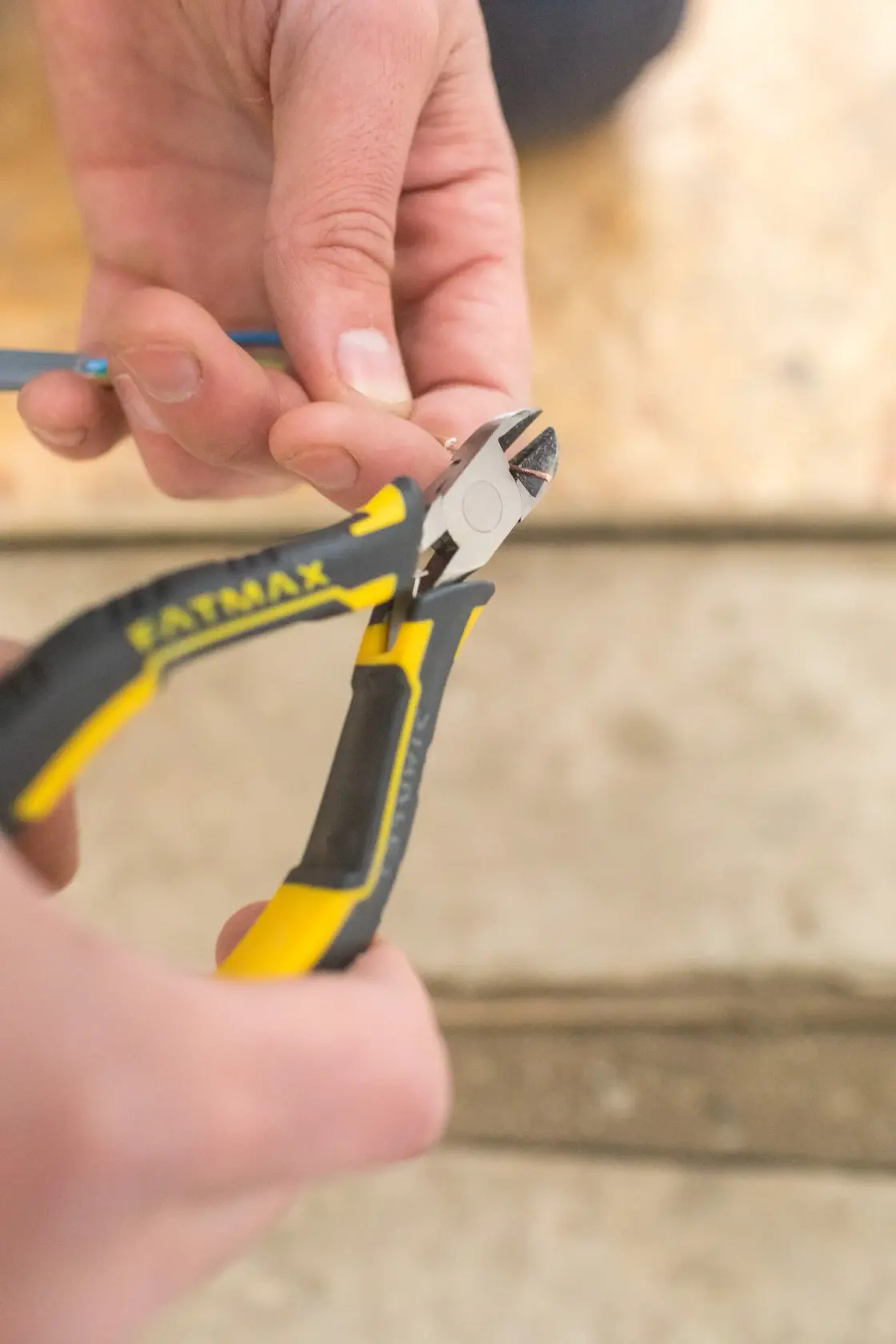 STANLEY FMHT0-80518 diagonal pliers cutting wire, close-up photography of black and yellow tool.