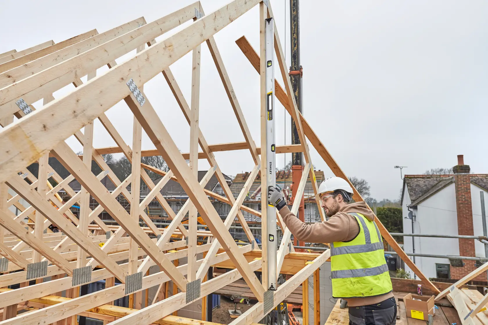STANLEY FMHT43679-1 Wasserwaage wird von Arbeiter mit Warnweste auf Baustelle mit Holzkonstruktion verwendet.