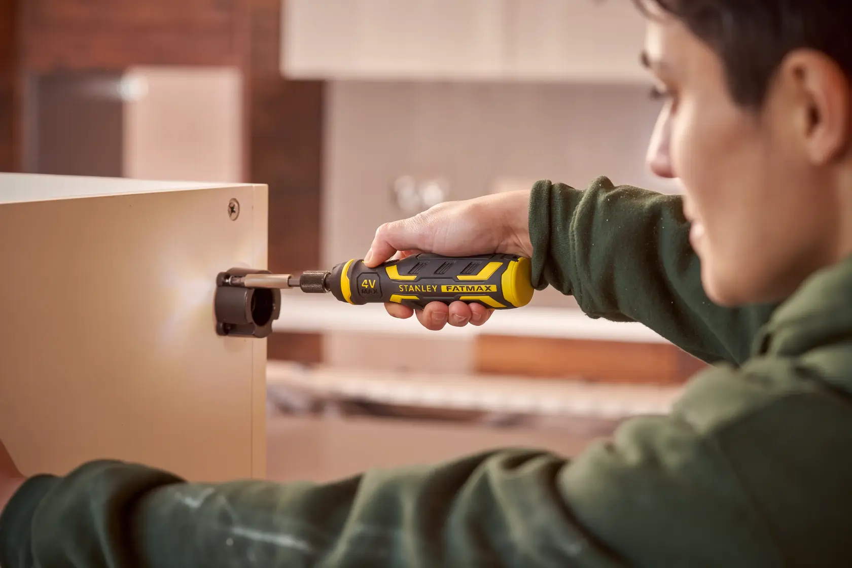 STANLEY FMHT66719-0 tournevis électrique utilisé sur une charnière d’armoire, poignée ergonomique jaune et noire.
