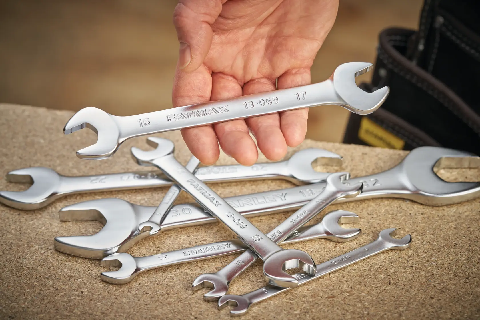 Photo of STANLEY FMMT13065-0 spanner set on workbench, one spanner held by hand, silver finish.