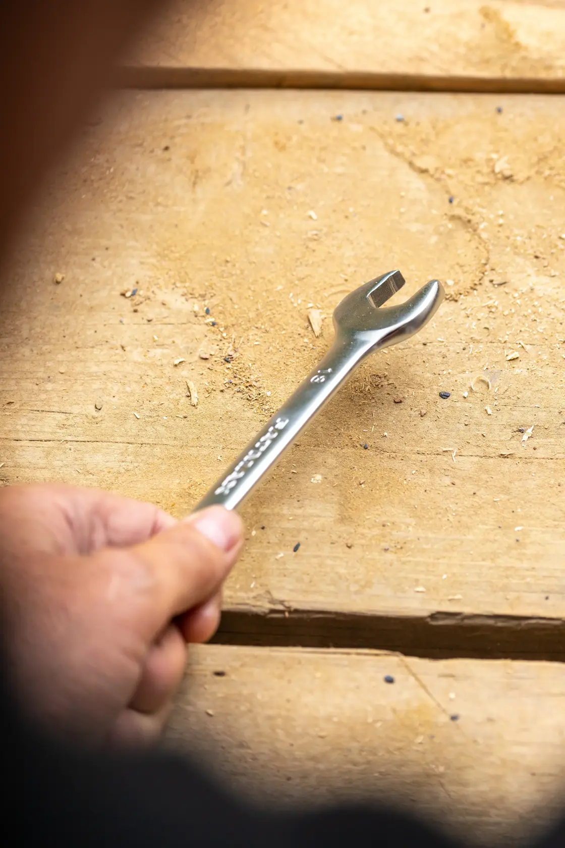 Photo of STANLEY FMMT13065-0 open-end wrench held over a wooden surface, product photography.