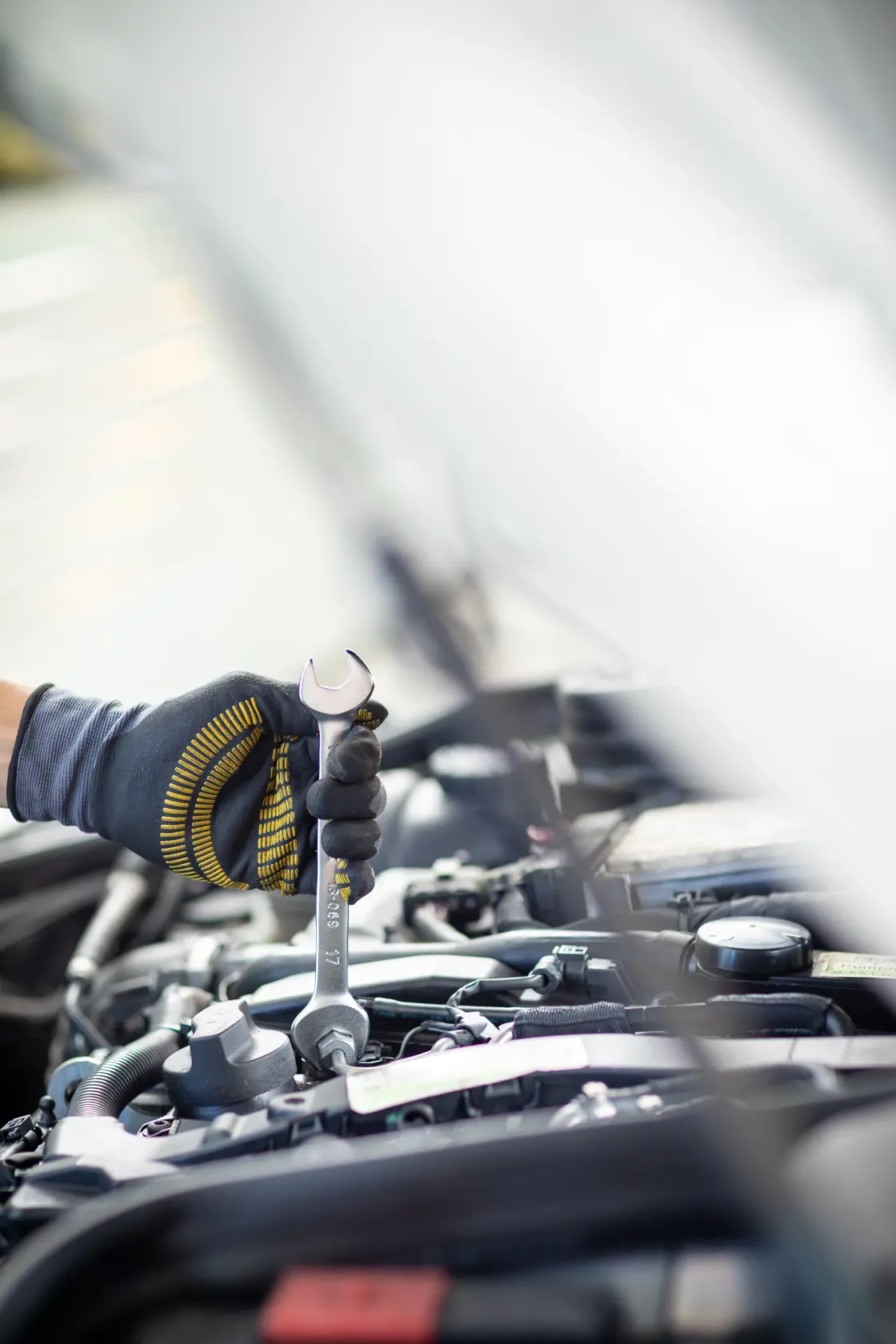 STANLEY FMMT13067-0 wrench held by gloved hand working on car engine, close-up photography.