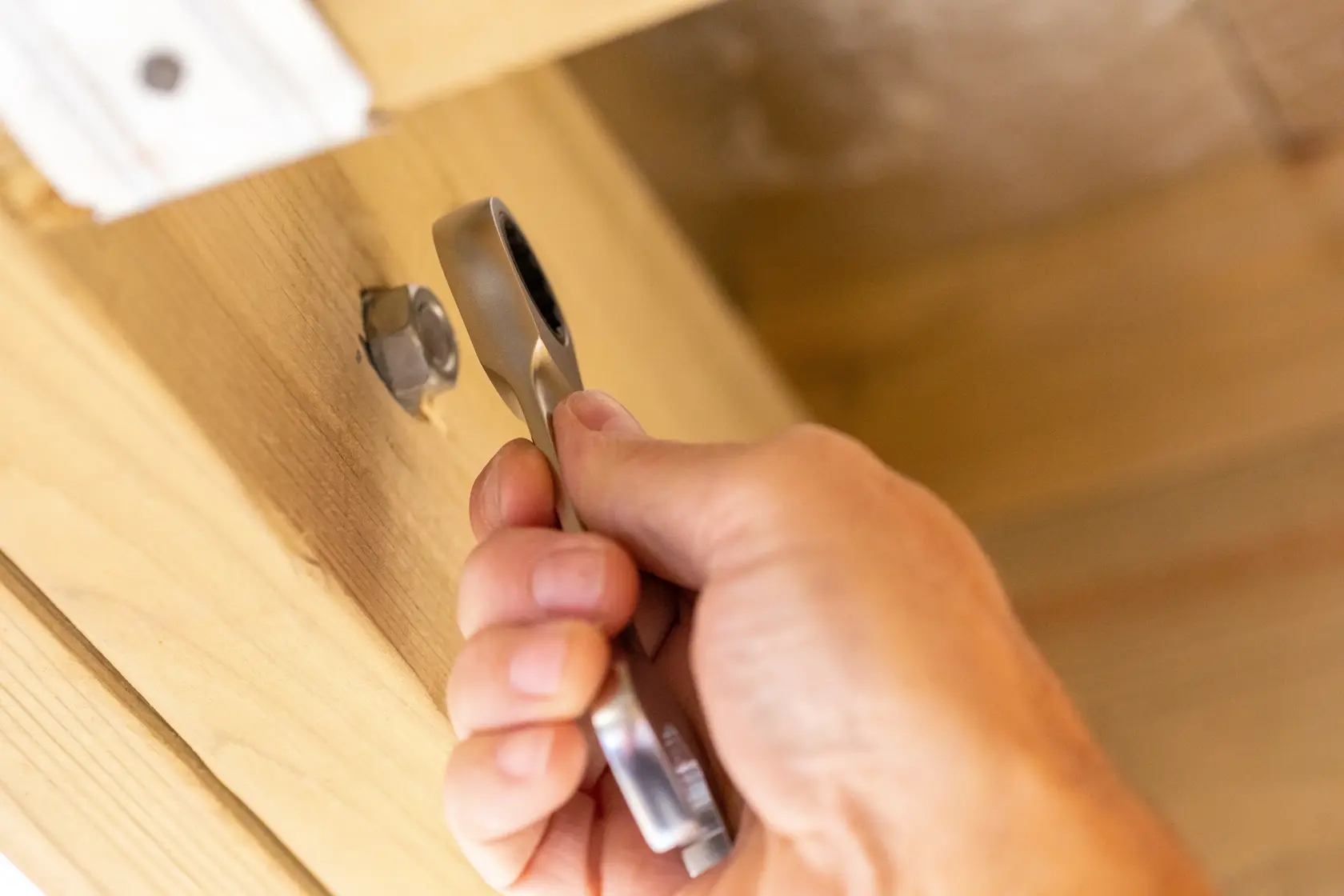 STANLEY FMMT13115-0 ratcheting wrench tightening a bolt on wooden surface, close-up.