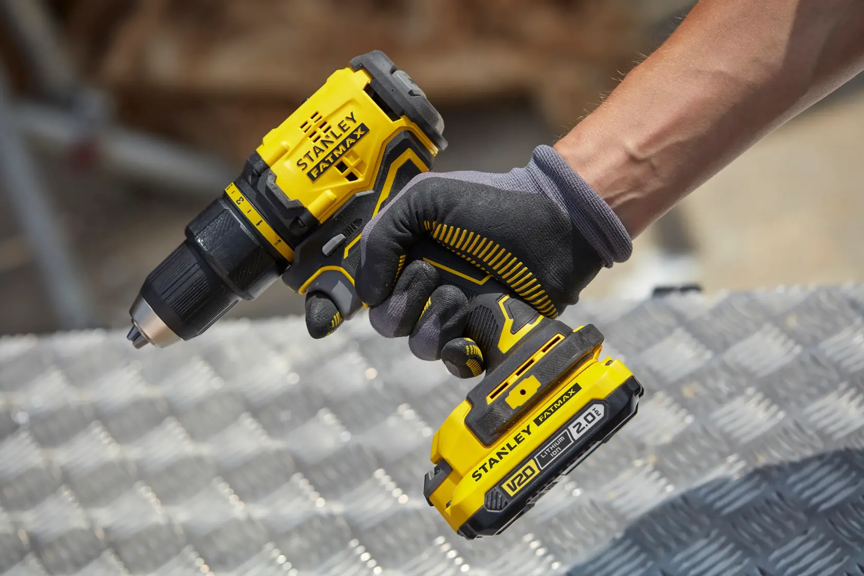 Photo de la perceuse sans fil STANLEY SFMCD710D2K, design jaune et noir, batterie visible, tenue par une main gantée.