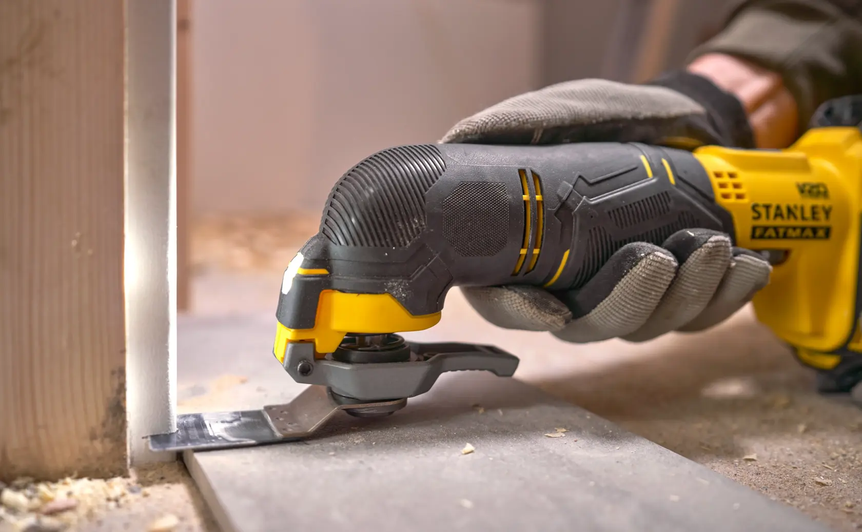 Stanley SFMCE500D1K outil multifonction oscillant en action, gros plan, découpe du sol en bois, photographie.