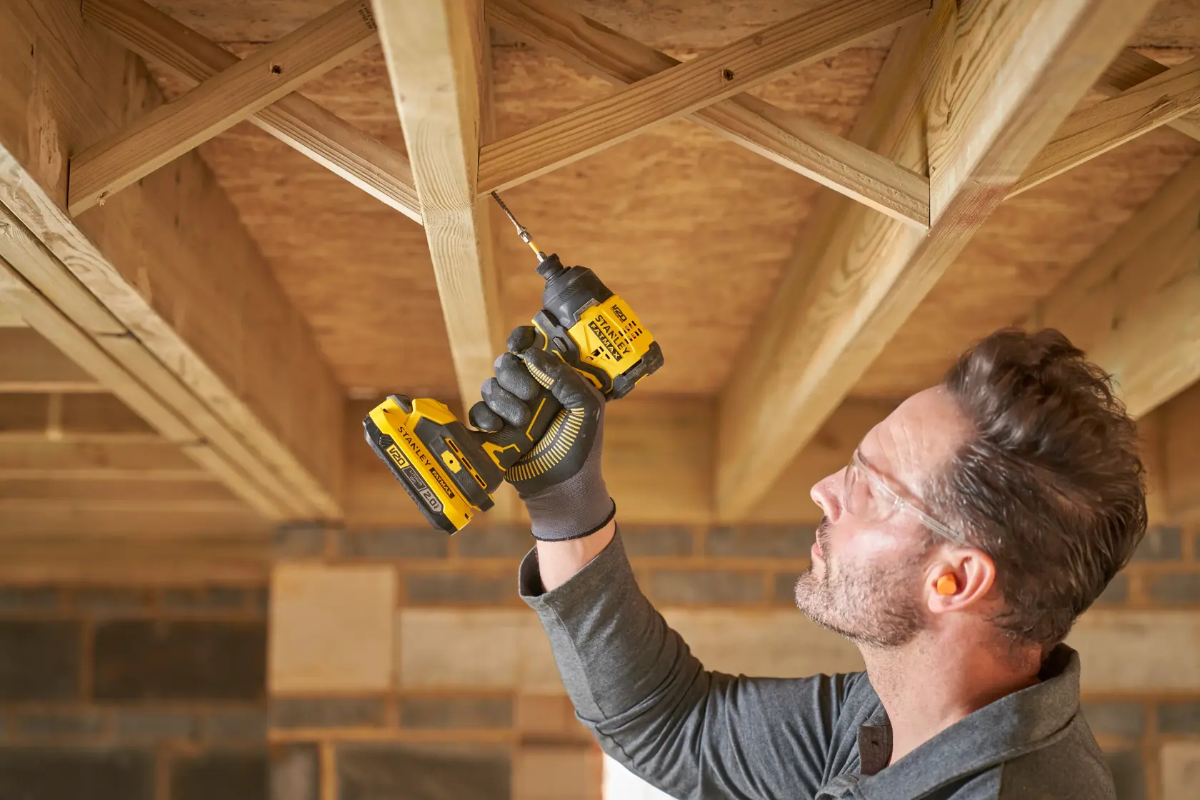 STANLEY SFMCF811D1T visseuse à chocs sans fil utilisée pour percer des poutres en bois sur un chantier.