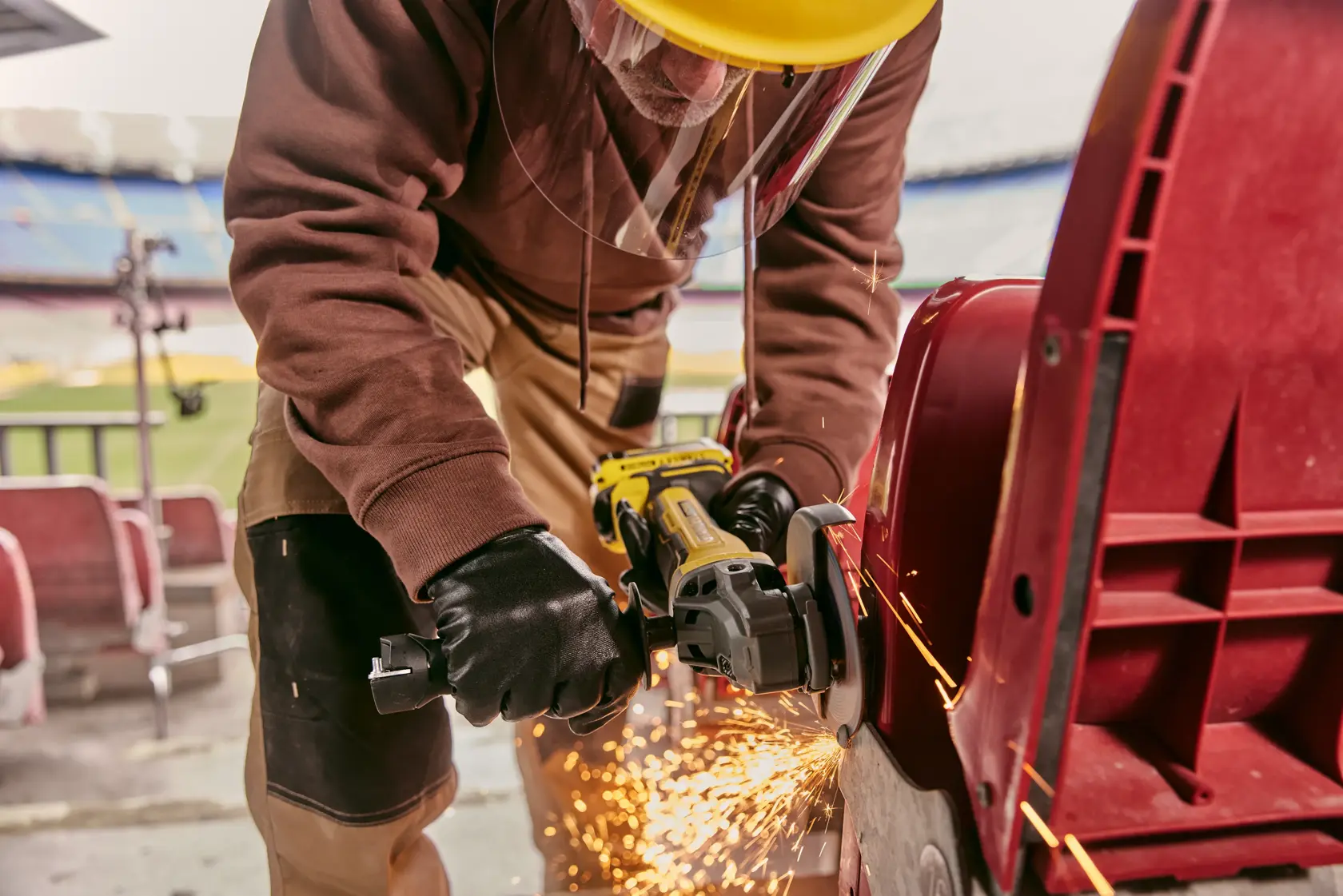 STANLEY SFMCG700M2K meuleuse en utilisation, ouvrier coupant du métal avec des étincelles, prise de vue rapprochée.