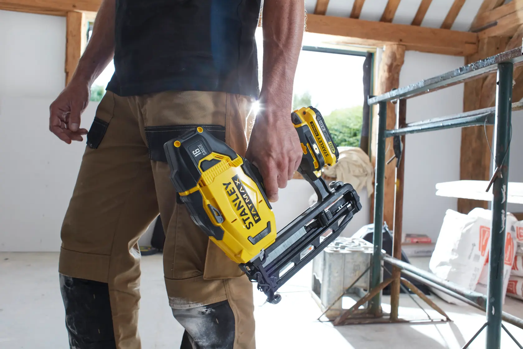 Photo de la cloueuse sans fil STANLEY SFMCN616B tenue par un ouvrier sur un chantier.