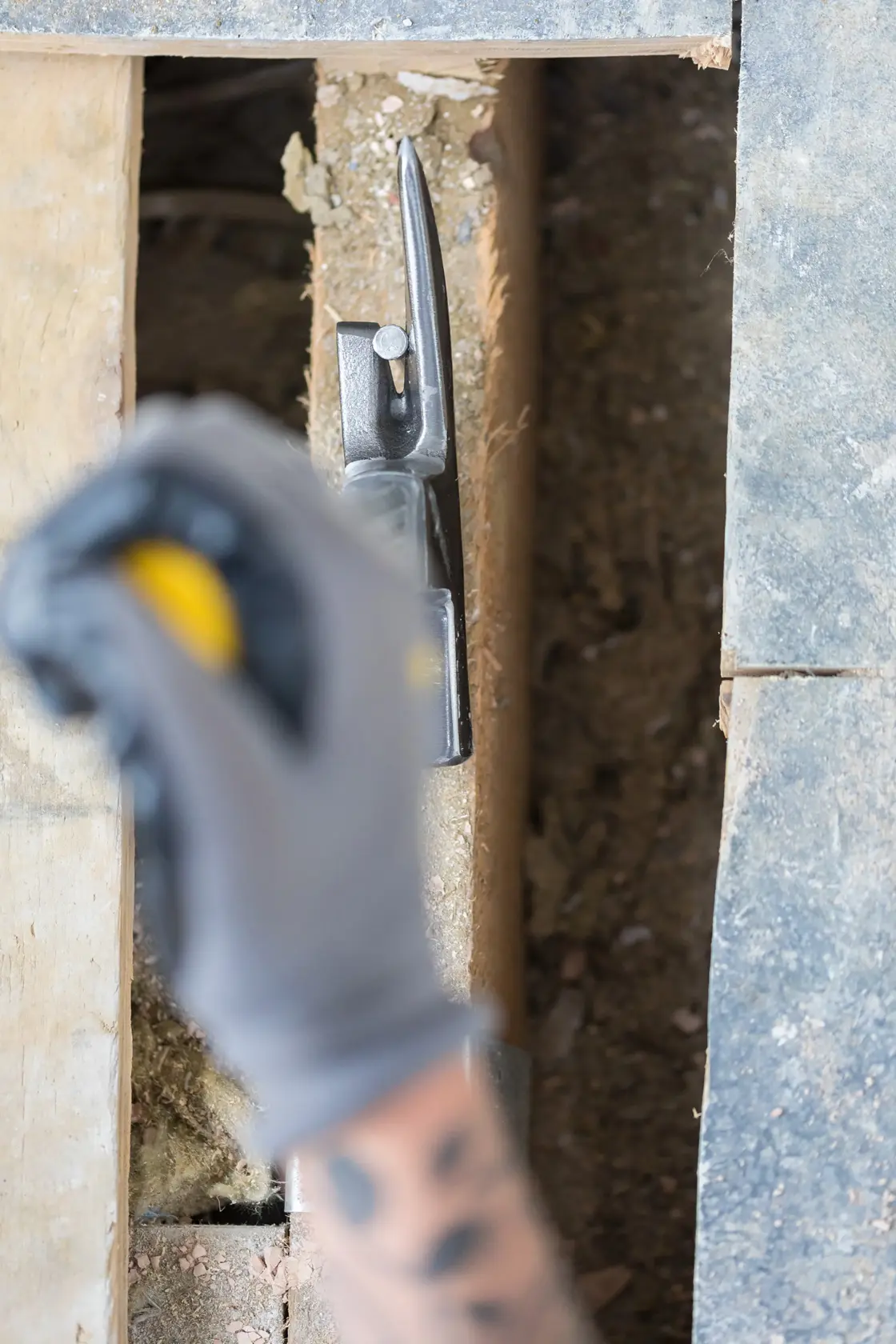 STANLEY STHT0-51312 Klauenhammer im Einsatz auf Holz während Bauarbeiten, Teilansicht mit behandschuhter Hand.