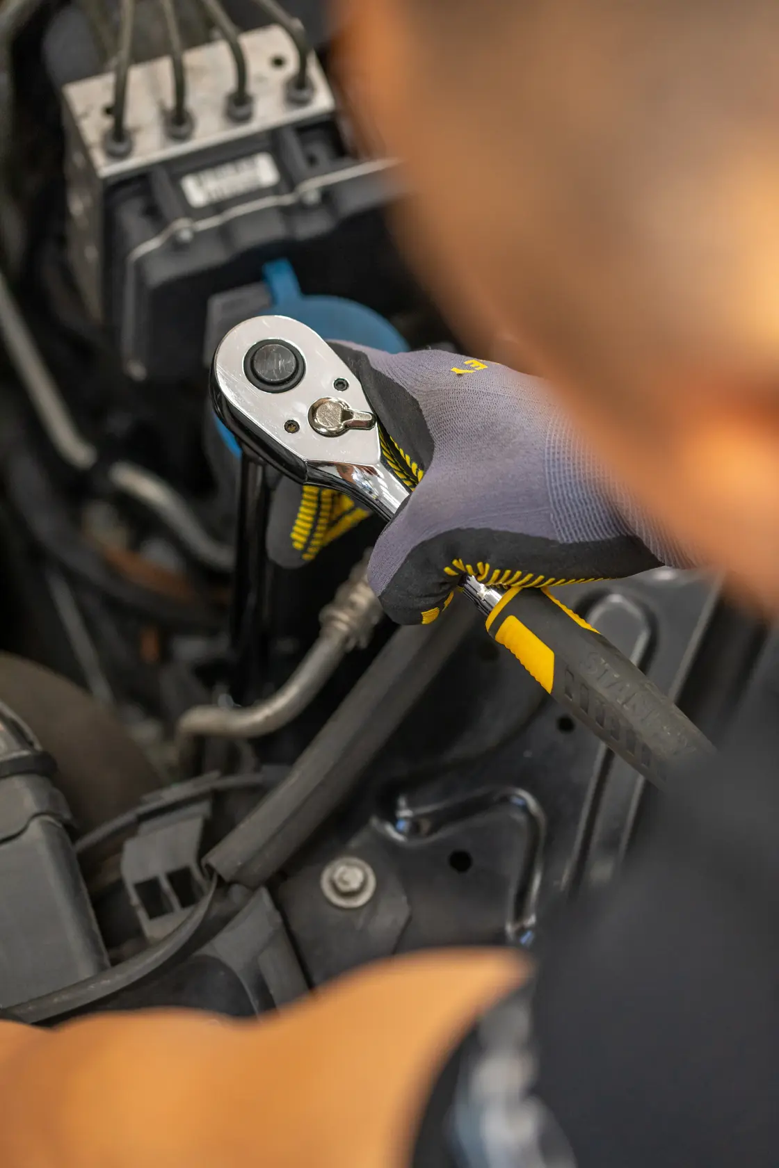 Photo of STANLEY STMT88942-0 ratchet wrench with yellow and black handle in use on car engine.